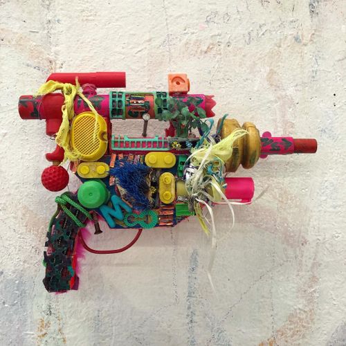 An object resembling a gun, made up of brightly coloured items