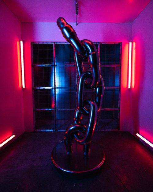 large sculptural chain in a neon room