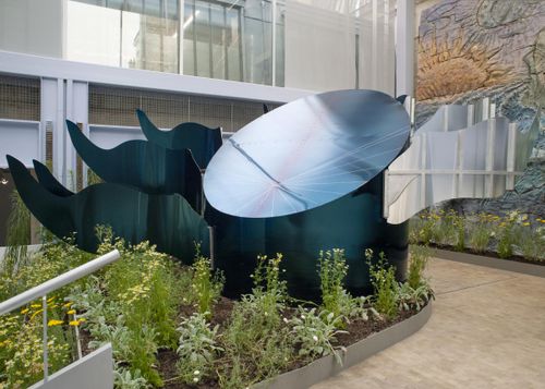 an outdoor installation of metallic shapes in a flower bed