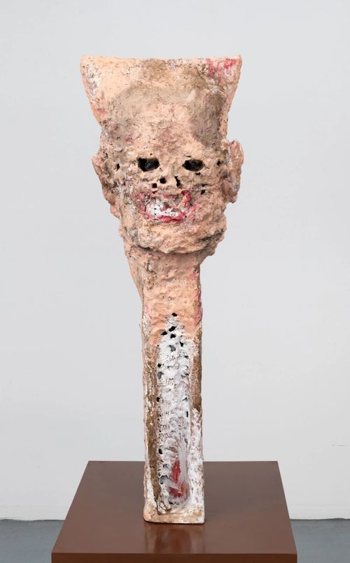 sculpture in flesh colours of a long neck with a head on top with distorted facial features