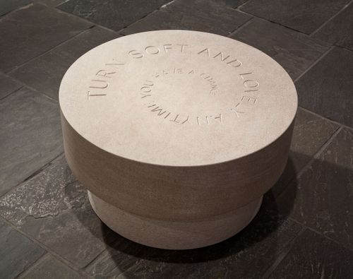 a round circular stone with text spiralling inwards and becoming smaller as it winds further into the centre