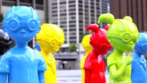 A close-up shot of six freestanding statues of young cartoon superheroes with goggles on in various colours (yellow, blue, red, green)