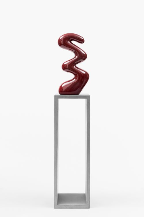 swirling shape red ceramic sculpture placed on a tall pedestal