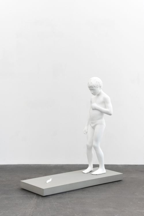 white sculpture of a child in a pair of briefs looking down at a slug in front of him