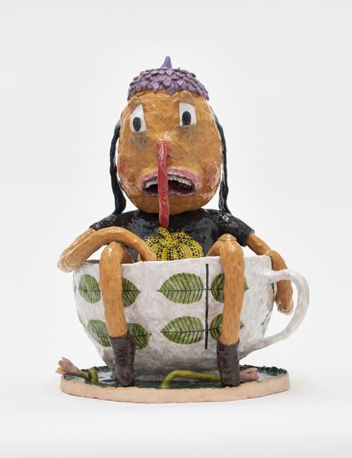 a figure with a long nose sitting inside a cup with leaf-pattern