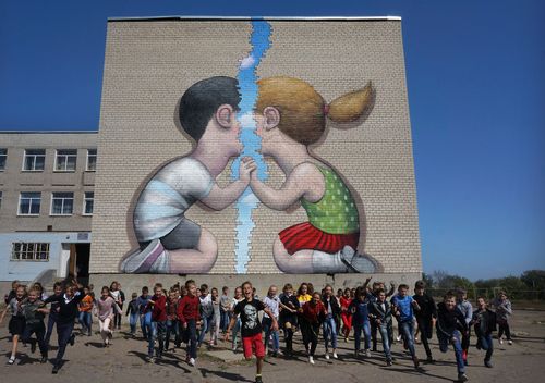 Artwork on a wall, two children leaning towards eachother with a large crack down the middle