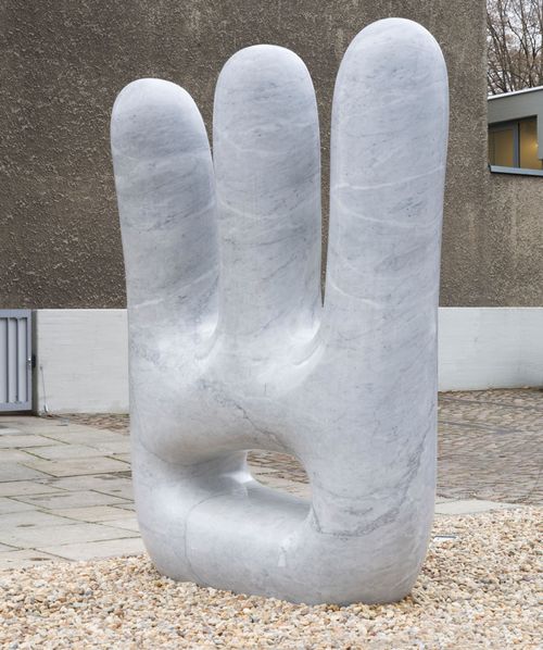 large block of marble placed outdoors with three vertical fingers