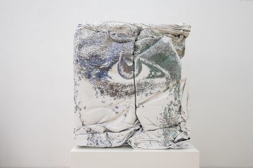 an eye painted onto a white textured, three-dimensional material, placed on a plinth