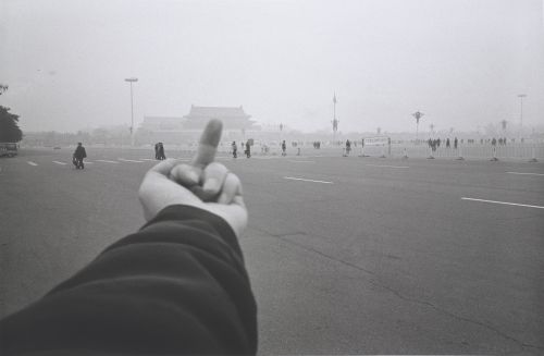 black and white photograph of a raised middle finger pointing towards Tiananmen Square, China