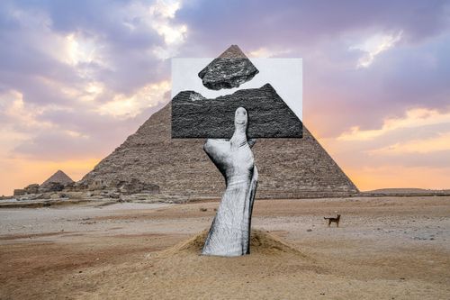 A hand holding an image in front of a pyramid