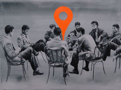 group of men sat around in a circle formation with a large orange map pinpoint placed in the middle