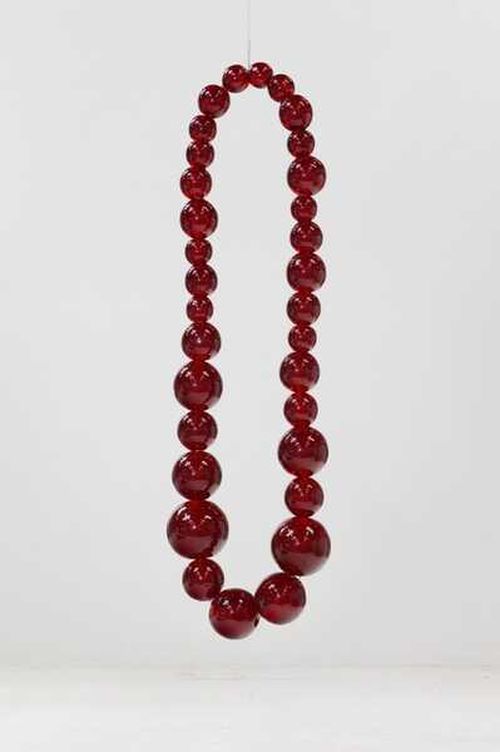 necklace hanging, formed of red beads of varying sizes