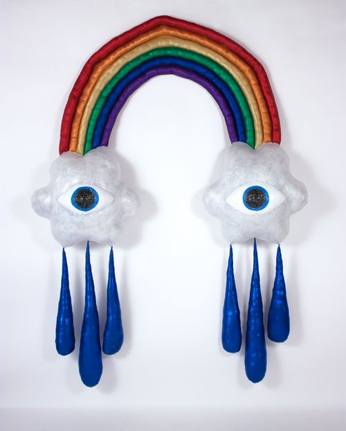sculpture of a rainbow with an eye in a cloud at each end and three drops of rain falling from each