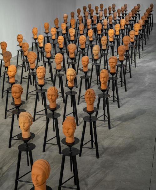 a room filled with only dozens of rows of sculpted busts placed on black stools