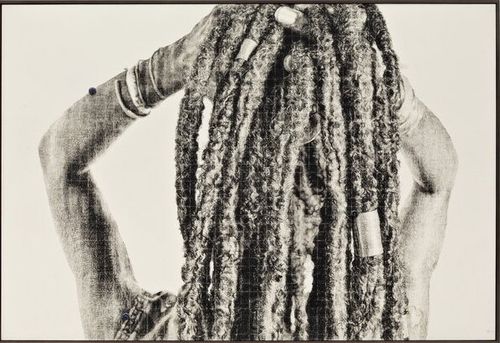 View of a woman from behind raising her arms upwards to lift up her thick braided hair