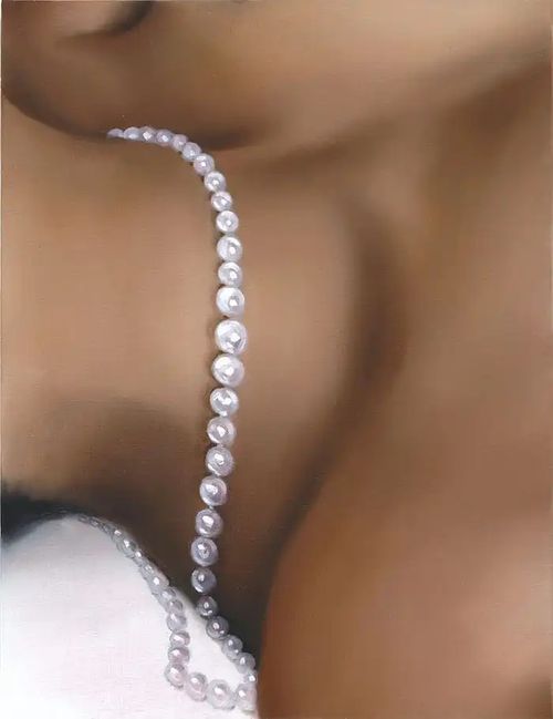 close-up view of a woman's flesh around her neckline as she lies horizontally and a necklace of pearls hang loosely around her neck