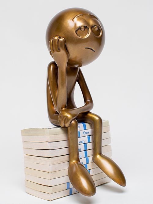 bronze figure sitting on books with his head in his hand