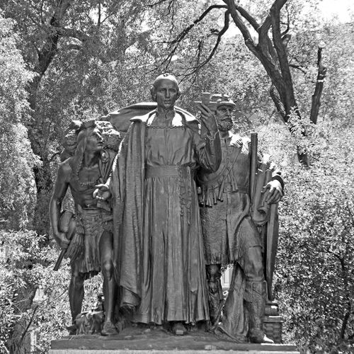 At the head of this large, multi-figure group French explorer and missionary Pere Marquette strides forward holding a Christian cross and looking straight ahead as if envisioning the historical consequences of his actions. To his left and slightly behind is cartographer, Louis Jolliet, holding several scrolled maps, also looking ahead. On Marquette’s right is the stooped figure of an American Indian, looking up at Marquette as if subservient or unenlightened.