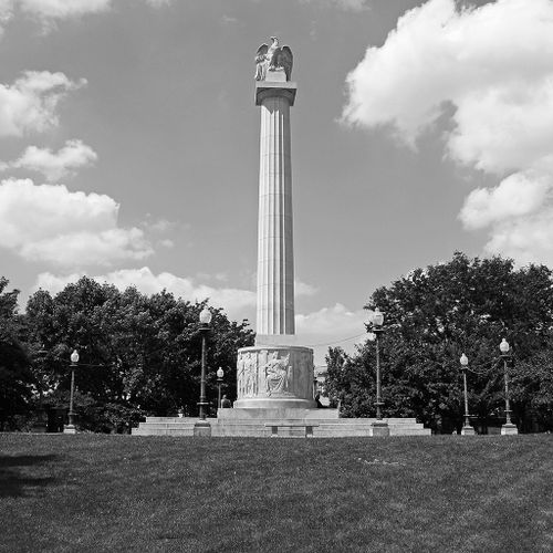 The Illinois Centennial monument is a fifty-foot high fluted column upon which stands an eagle with its wings somewhat spread, as if landing, or about to take off. At the base of the column is a six-foot high drum that shows pioneers, explorers, American Indians, laborers, and farmers carved  in low relief. The sculptural ensemble rests on a broad, stepped plinth.