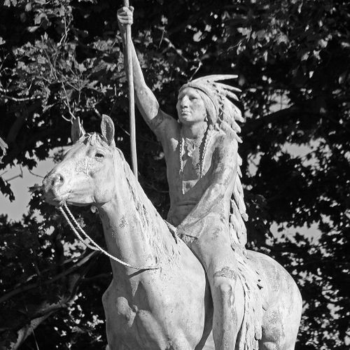 A Signal of Peace is a simple figural grouping of an Indian chief mounted on a stationary horse. The Indian wears an elaborate and long feathered headdress and holds a staff with his upraised right hand. Both rider and horse look ahead resolutely.