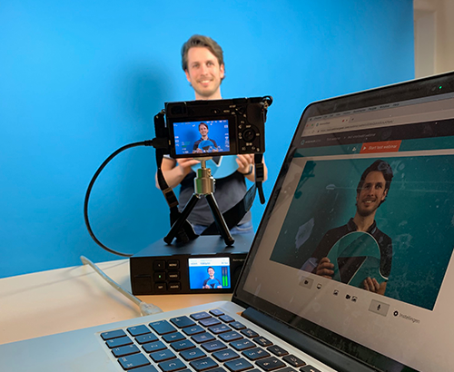 A camera with a man behind connected with the laptop