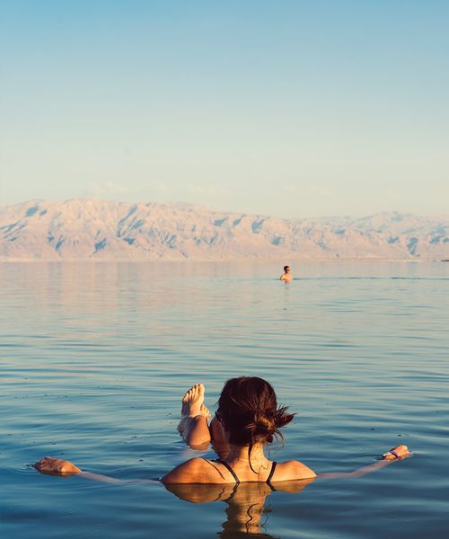 swimmer floating in the dead sea in israel during the evening