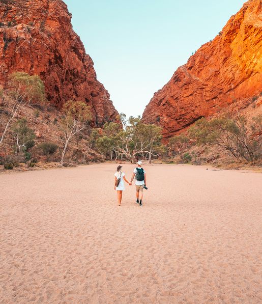 Young couple holding hands and walking towards Simpsons Gap