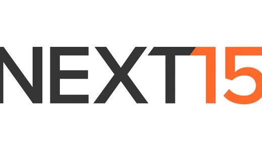 The Next15 Communications PLC logo is seen in a potent contrast of black and orange.