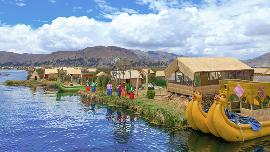 yellow boats in front of a village in lake titicaca peru