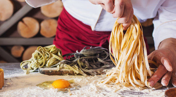 a chef making pasta by hand on a floured kitchen surface