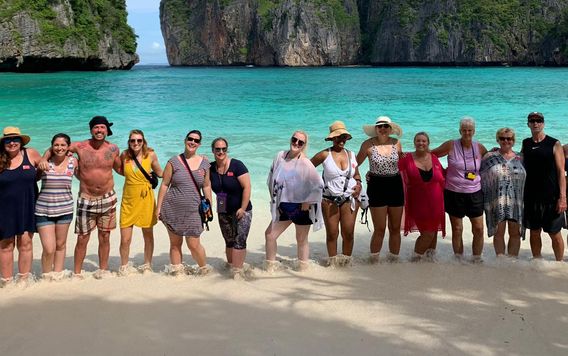 group of travelers standing together on the beach at Maya Bay in Thailand