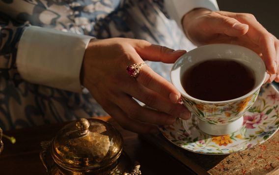 close up of hands with gold rings on holding a cup of tea