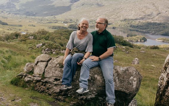 couple of travelers sitting a on a rock in ireland together