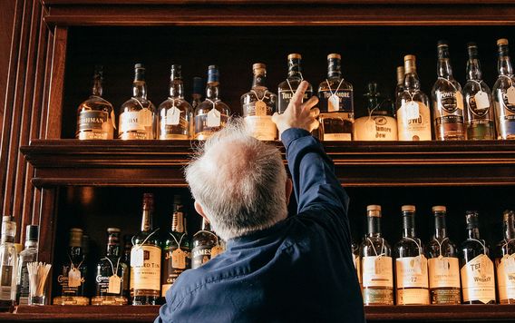 man reaching for liquor in an irish bar