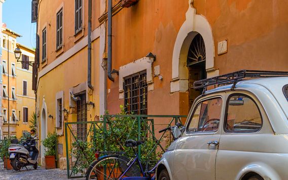 white italian car parked on a cobblestone street in trastever rome