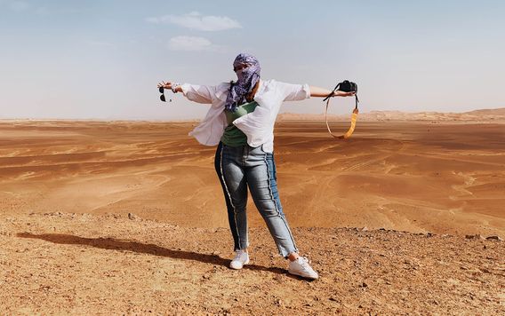female traveler holder her arms up in the sahara desert in morocco