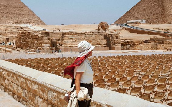 woman with a hat scarf on looking at the pyramids in egypt