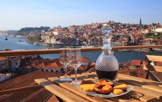 two glasses and vase of port wine on table roof top in porto portugal