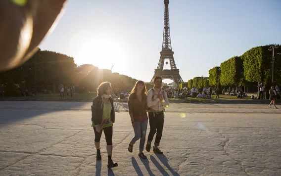 three people walking in front of the Eiffel tower in paris france
