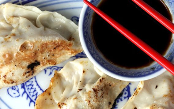 potstickers on blue and white dish and red chopsticks resting on cup of soy sauce