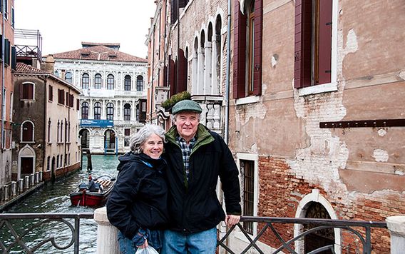 couple standing on a bridge over a canal in venice italy