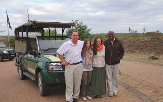 two group travelers with staff members with safari truck behind them