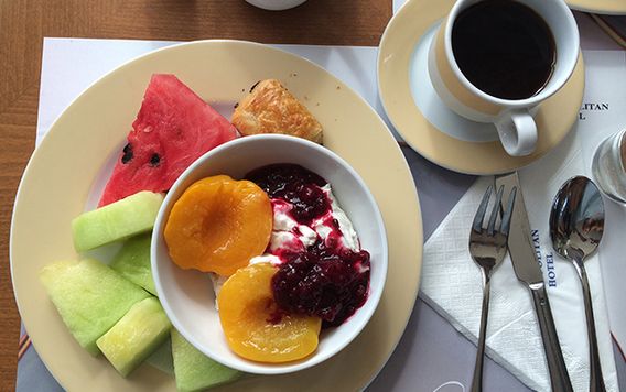 over head view of plate of fruit with yogurt and pastry with a cup of coffee