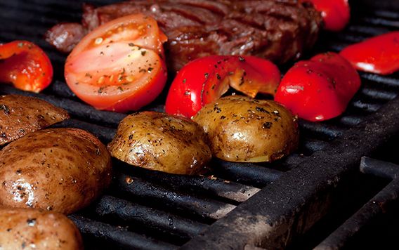 steak tomatoes and potatoes on a grill