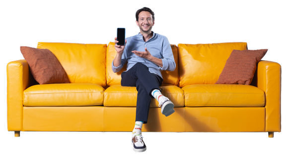 Tomáš Srovnaný na žlutém gauči s mobilem v ruce