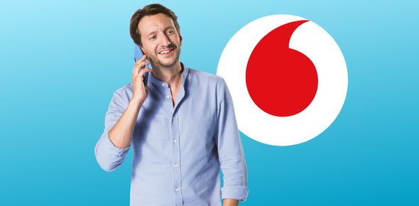 Tomáš Srovnaný s telefonem a logem Vodafone v pozadí