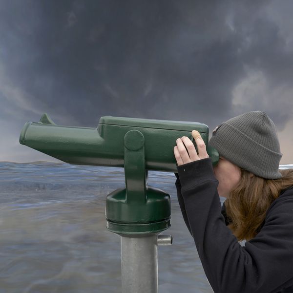 Photo of a person looking through binoculars in front of water. | Image by ©Verena Tscherner and Joerg Auzinger