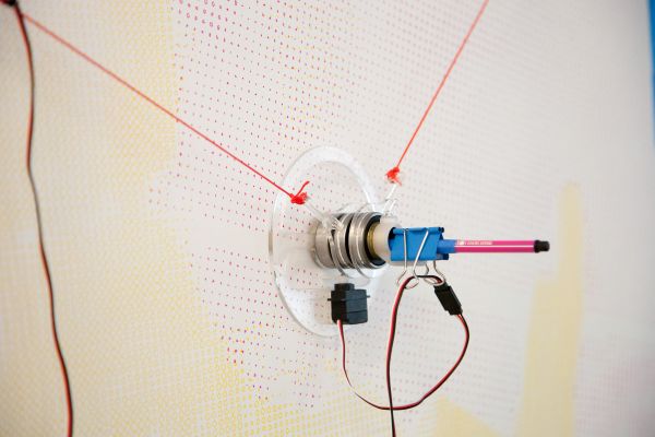 little motor holding a pen over paper | Image by ©