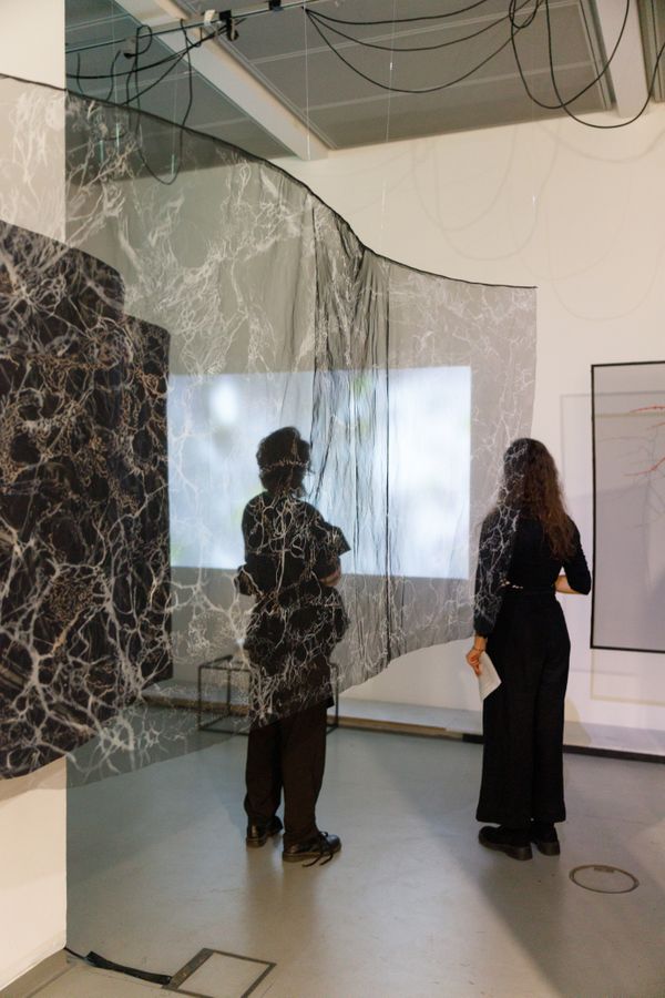 Installation of hanging fabric with projection in the background | Image by ©