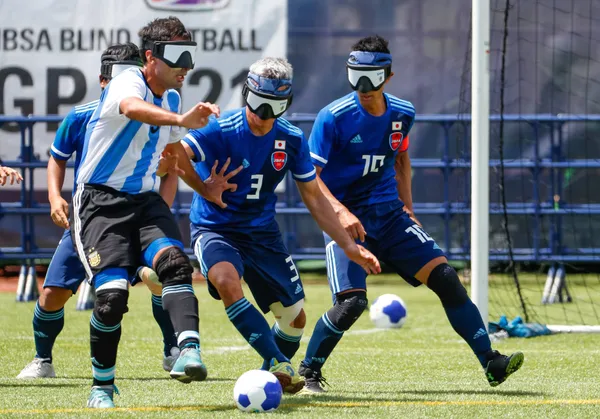 4 Sportsmen in blue uniform playing Football 5-a-side, fighting for the ball
